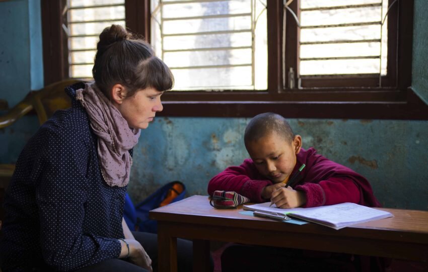A group of volunteers working together to assist with daily tasks and maintenance at a traditional Nepalese monastery in the mountains